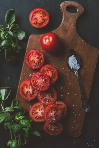 红色西红柿, 罗勒叶和盐在切板勺上的顶部视图