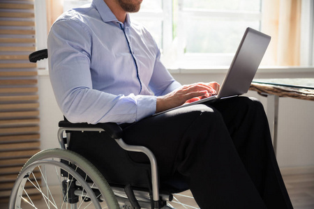 残疾商人坐在轮椅上使用笔记本电脑