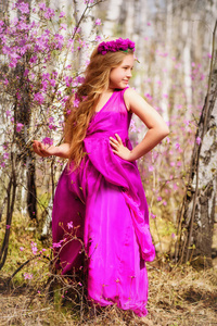 一个孩子站在杜香和桦木在粉红色的礼服和微笑