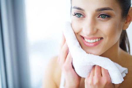 脸干燥洗脸.愉快的妇女干燥皮肤用毛巾照片