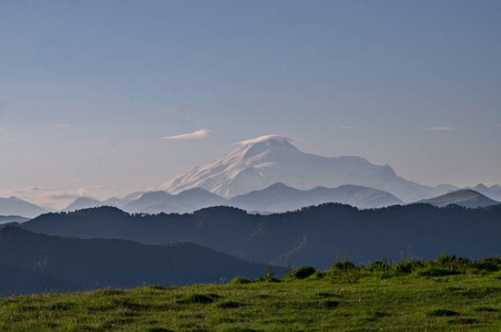 雪山顶 Elbrus 的背景下, 许多斜坡和一个绿色的草地背景图片