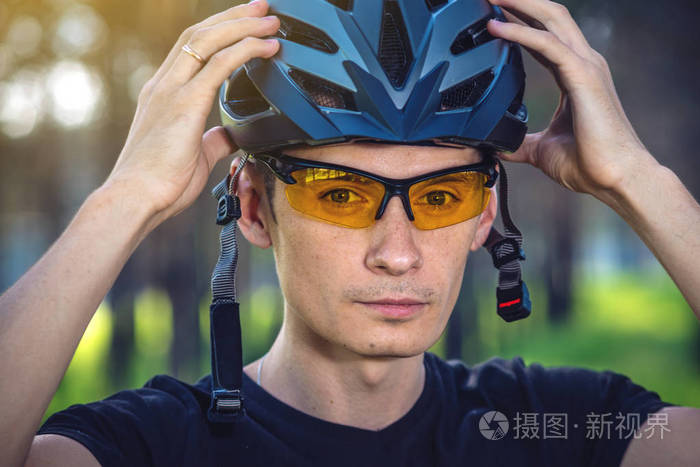 骑自行车的人在绿色自然的背景下戴着一顶运动的灰色头盔。山地自行车的强制保护概念