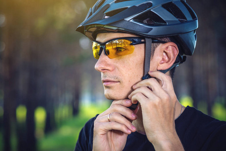 骑自行车的人在绿色自然的背景下戴着一顶运动的灰色头盔。山地自行车的强制保护概念