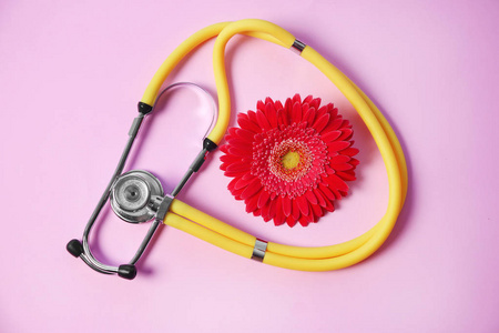 在色彩背景下, 用听诊器和花朵平躺在一起。妇科检查