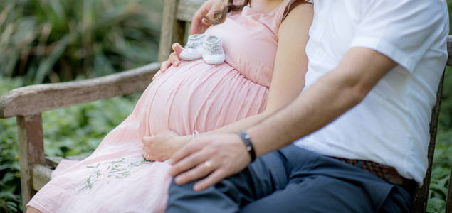 愉快和年轻怀孕夫妇拥抱在自然细节年轻怀孕夫妇新的家庭