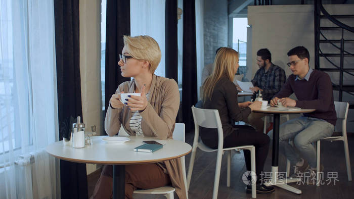 年轻漂亮的女人坐在桌前,喝咖啡室内照片-正版商用图片0unci0-摄图新