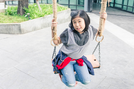 亚洲女孩坐在链摇摆木