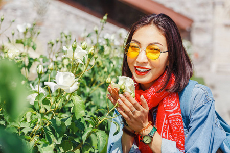 亚洲旅行妇女在庭院嗅到的白色玫瑰花