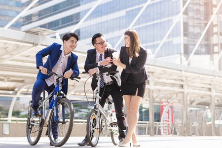 亚洲青年商务小组在城市骑自行车时放松说话