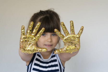 快乐的孩子与金色的油漆在他们的手掌。创意理念