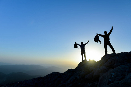 背包徒步旅行者站在山顶上举起双手, 欣赏风景
