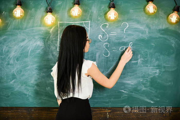 数学老师在黑板上写字, 后面看.女士性感的老师在眼镜解释公式.
