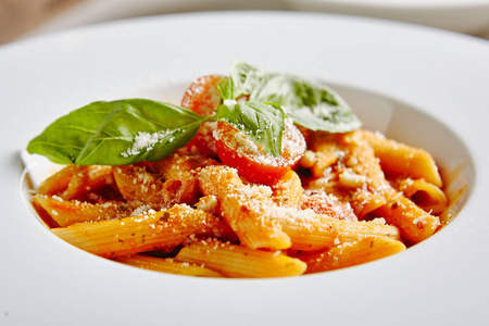 番茄通心粉面食铝劲番茄酱, Parmigiano Reggiano 奶酪, 樱桃西红柿和罗勒在白色的盘子关闭。传统意大利通心粉在