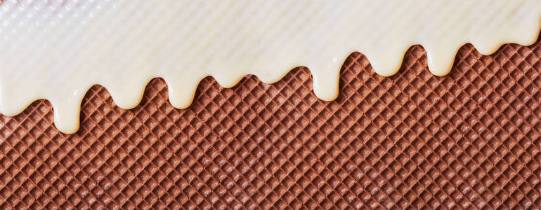 饼干覆盖了炼乳特写.白色热巧克力在晶片上扩散照片