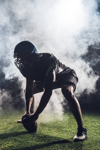 运动美式足球运动员的剪影在星位置反对白色烟雾