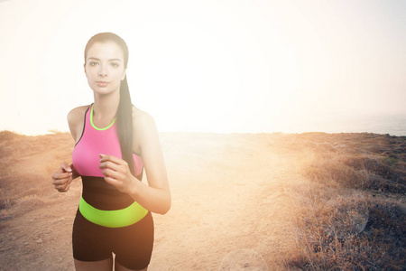 跑步的女人。夏季阳光明媚的早晨, 在山区和海上的小径上慢跑的年轻女性模特。健身。健康的生活方式