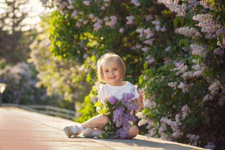 美丽的小女孩与一束丁香花在阳光明媚的日子里