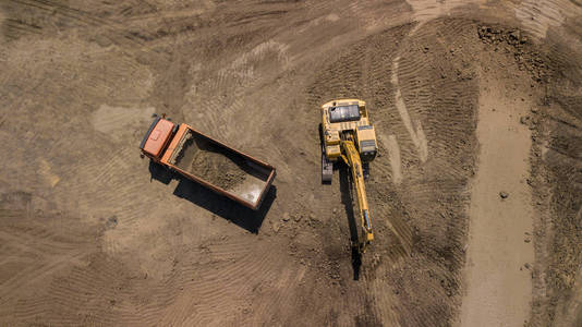 挖掘机的鸟瞰把沙子倒进卡车里。 在监狱里