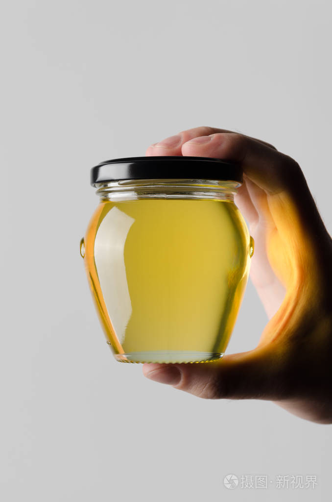 蜂蜜罐子模型-男性手拿着一个蜂蜜罐子在灰色背景上