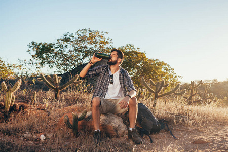 在巴西 Caatinga 徒步旅行时, 男子休息喝瓶装水