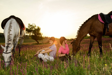 两个女人和两匹马户外在夏天快乐的日落一起自然