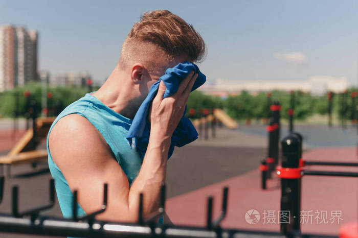 一个年轻人在锻炼后擦拭了他脸上的毛巾汗.