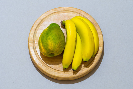 成熟的黄色香蕉和一个木瓜在圆木盘上隔离在背景上, 文本复制空间照片