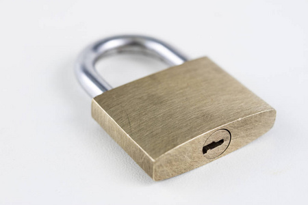 白色桌子上的黄铜挂锁。用于锁定和防止入室盗窃的附件。白色背景