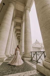 美丽的年轻新娘在婚礼礼服在梵蒂冈柱廊