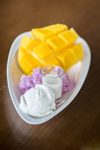 糯米芒果配椰奶, 泰国甜点放在白盘子木桌上。seclective 焦点