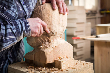 关闭年轻人木匠在工作衣裳锯一个人的头用一棵树, 用凿子在车间里, 在