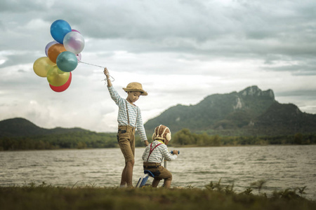 两个小亚洲孩子在海滩上有气球, 有很大的假期时间。
