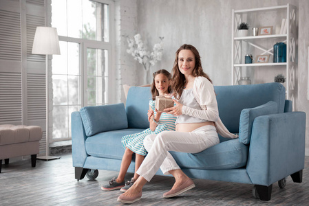快乐的生日妇女坐在客厅与她的女儿