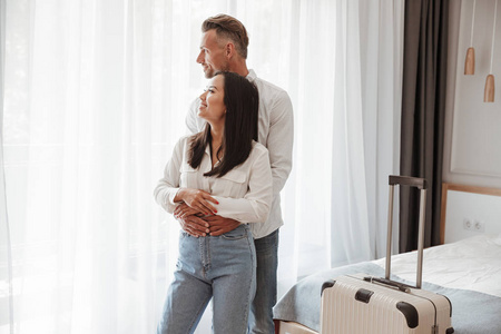 照片的迷人夫妇男女在休闲牛仔裤的衣服拥抱在一起, 在酒店房间与大