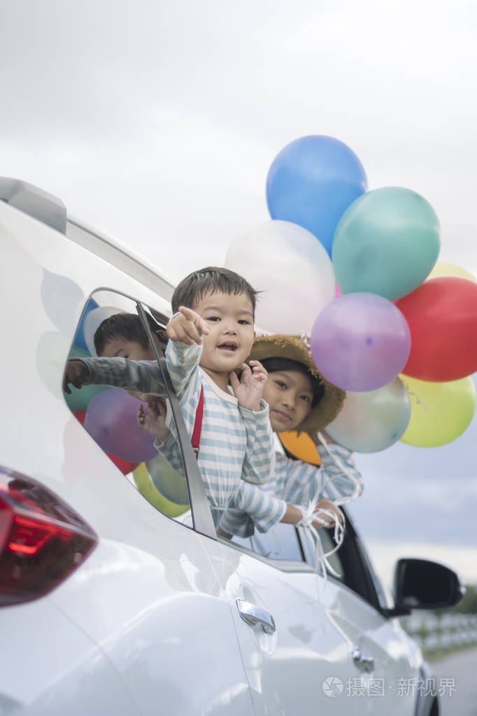 两个可爱的男孩在车上五颜六色的气球