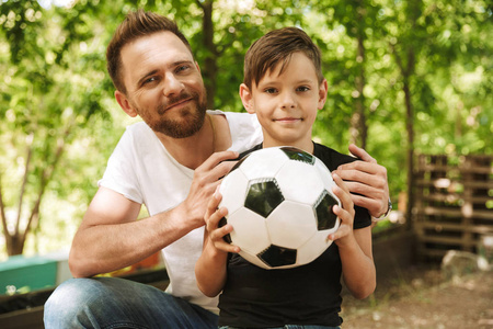 快乐的年轻父亲的图片与他的小儿子在户外公园自然与足球球的乐趣