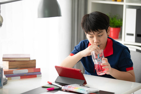 亚洲男孩在家中喝酒看平板电脑
