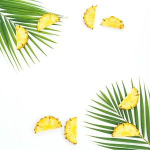 在白色背景下切片的菠萝水果和棕榈叶的框架。平躺, 顶部视图。热带概念