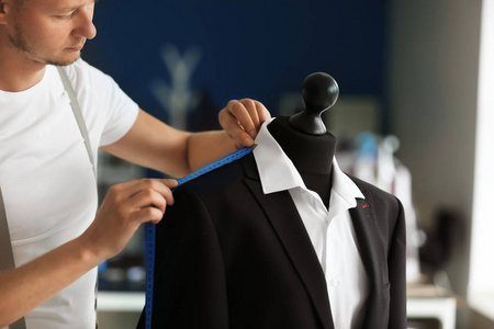 人的西装衣服画年轻裁缝在画室里对人体模特的男夹克做测量照片