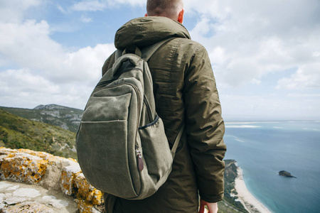 一个游客或一个背包的旅行者站在山顶上, 欣赏大海或大海的美丽景色。步行或徒步旅行