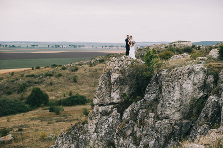 美丽快乐的新婚夫妇拥抱在悬崖上