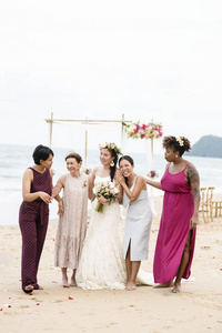 美丽的新娘与她的母亲和客人在海滩婚礼