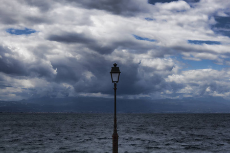 一盏孤独的灯笼, 衬托着大海和戏剧性的天空。路特奇, 希腊, 多云的夏日