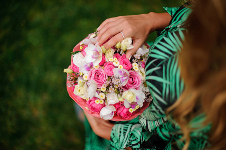 顶部的女孩在黑暗的热带礼服手持在她的手一个美丽的盒子粉红色的玫瑰和白色的兰花在公园里