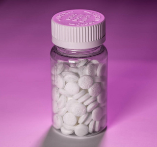 粉红色背景的白阿司匹林药片瓶