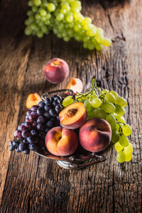 成熟的葡萄和桃子在乡间的碗和木桌上