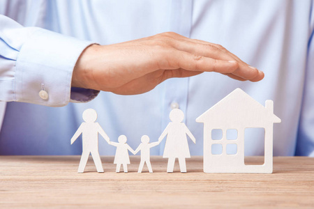 人保护他的房子家庭保险和家.穿衬衣的男人用房子盖住他的家人.照片