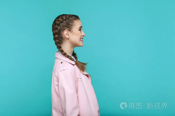 蓝色背景下带有辫子发型的年轻女子笑脸微笑的侧面图