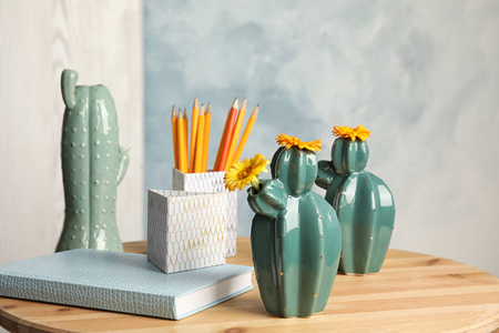 时尚的仙人掌形状的花瓶和文具在桌子上的室内。创意装饰