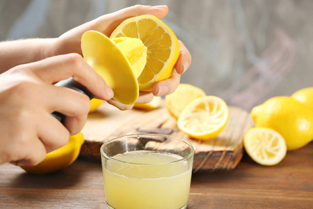 铰刀用铰刀挤柠檬汁的年轻妇女桌上的玻璃照片